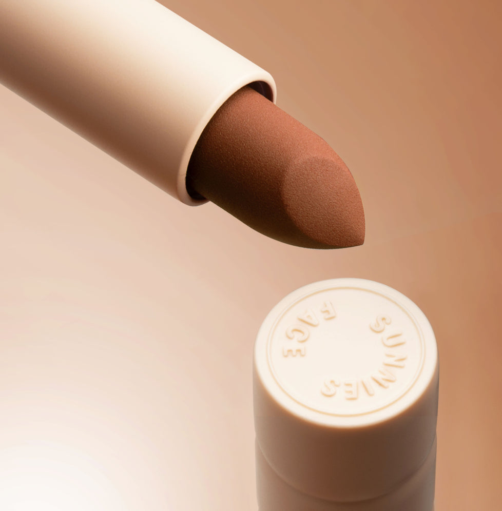 Lottiee Duty Organic Waterproof Matte Lipstick shown with a cream-colored tube cap revealing the lipstick bullet in a neutral brown shade. The packaging features a simple design with a smooth finish.