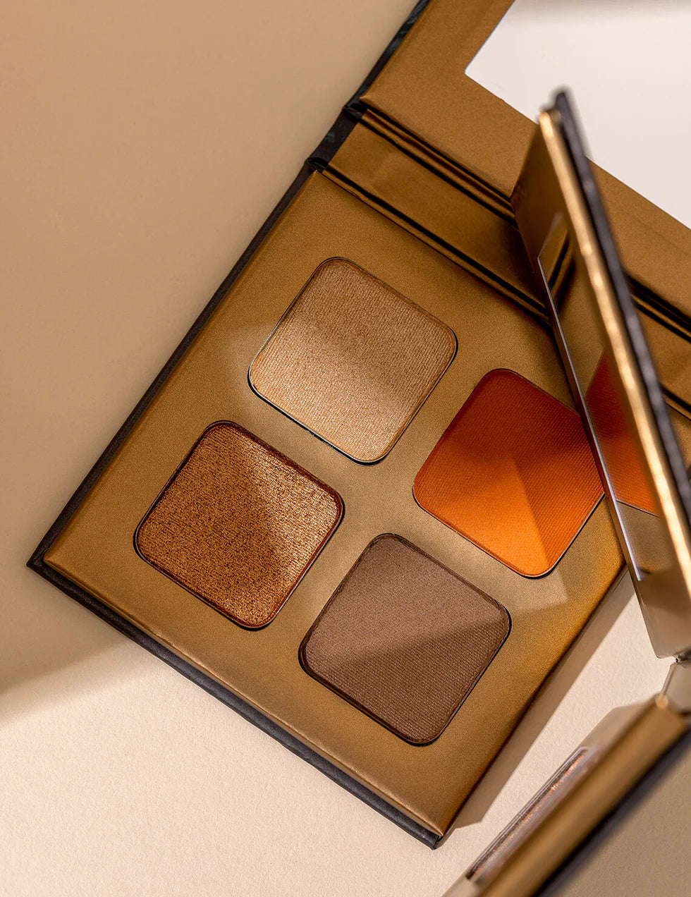 Lottiee Duty Eye Shadow Palette featuring four shades: a matte orange, a shimmer beige, a matte deep brown, and a shimmer copper. The palette is housed in a gold-colored compact with a mirrored lid for easy application.
