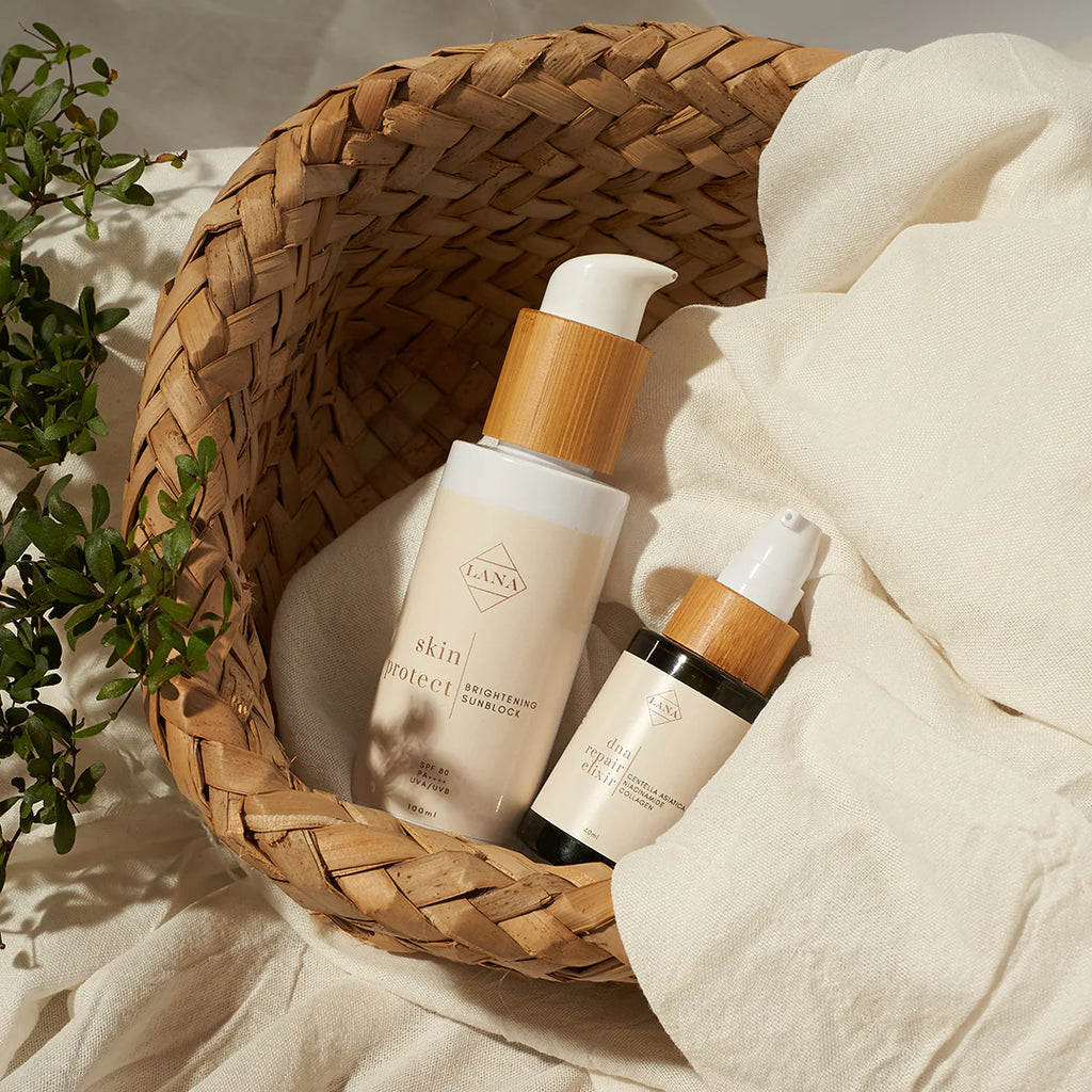 Lottiee Duty Lux Glow Sunblock Cream in a beige bottle with a bamboo lid, placed in a woven basket alongside another product. The cream is designed for skin protection and moisturizing.