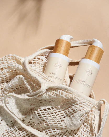 Lottiee Duty Lux Glow Sunblock Cream in a sleek bottle with a bamboo cap, shown nestled in a beige mesh bag. The product is designed for skin protection from sun damage.