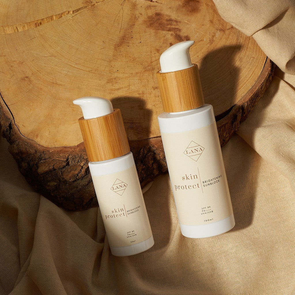 Lottiee Duty Lux Glow Sunblock Cream, presented in two bottles with bamboo caps. The cream features the brand's logo and is set against a natural wood background, enhancing its organic appeal.